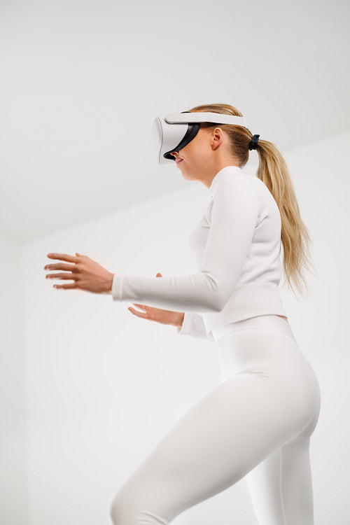 Woman in White Using Virtual Reality Headset in Bright White Room