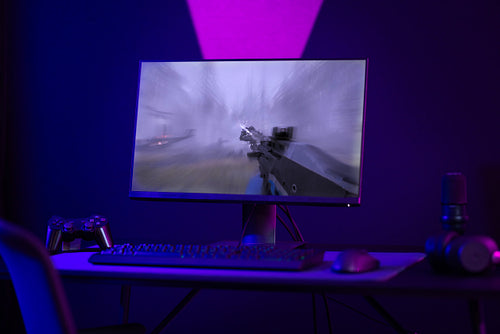 Colorful e-sport gaming and streaming studio with first-person shooter online video game on computer monitor