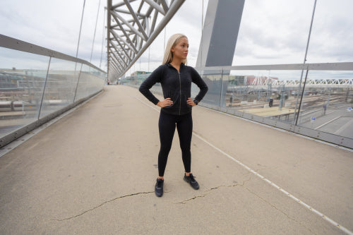 Blonde Female Beauty in Black Workout Wear Standing At Modern Bridge In City