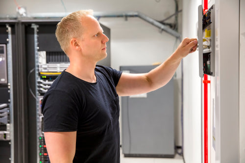 Confident Male Technician Opening Fire Panel In Datacenter