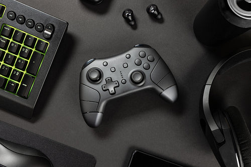 Game controller with green lit keyboard amidst various wireless devices