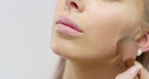 Close-up of a beautiful young woman applying dry cosmetic tonal foundation