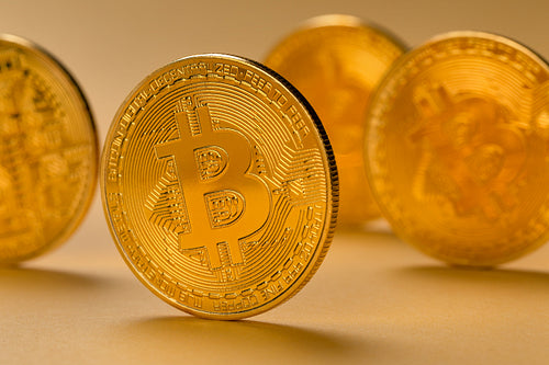 Closeup of gold bitcoin standing on yellow backgound