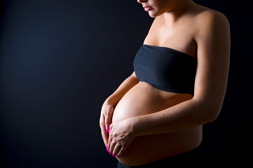Pregnant woman with her hands on the bare belly