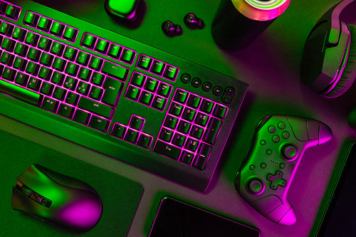 Purple lit keyboard amidst various wireless devices