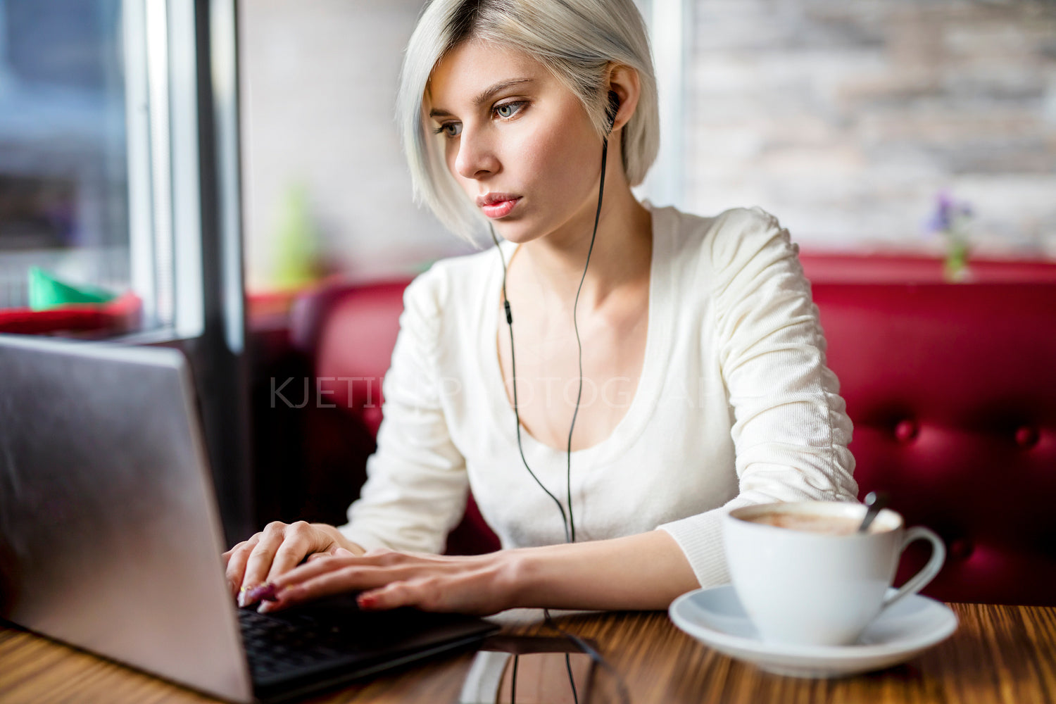 Woman Listening Music While Working On Laptop In Cafe