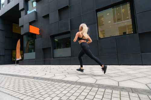 Back view of a fast running fit woman in modern city environment