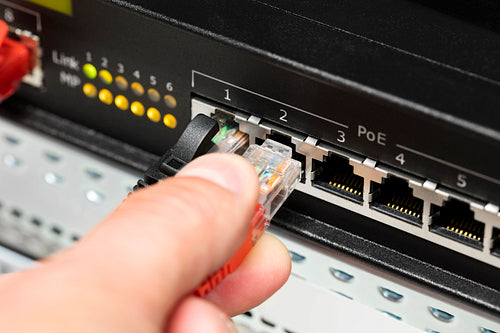 Computer Technician's Hand Inserting Cable Into Switch