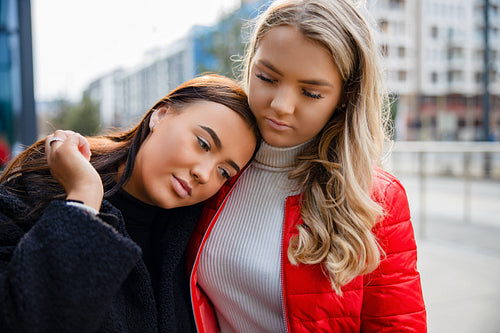 Caring Friend Consoling Unhappy Young Woman In City