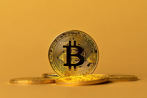 Closeup of gold bitcoins on yellow backgound