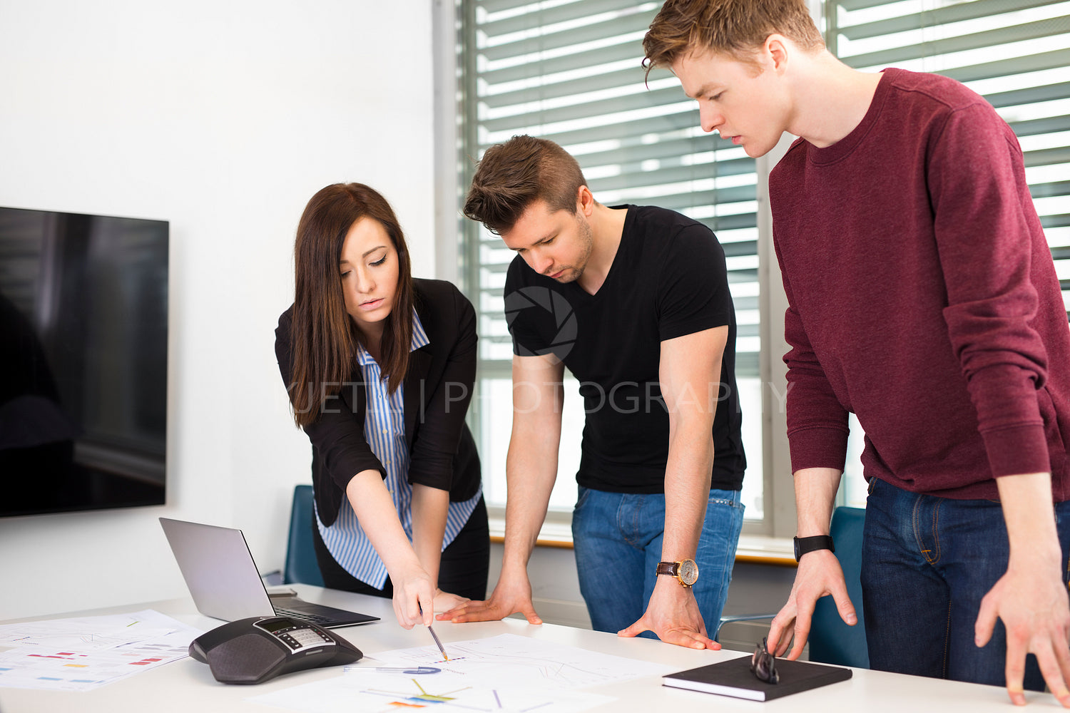 Businesswoman Explaining Plan To Male Colleagues At Desk