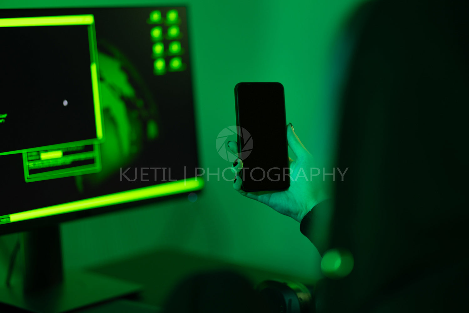 Cyber security concept showing hacker holding mobile phone in dark room
