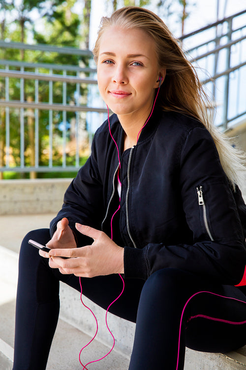 Beautiful Runner In Sportswear Listening Music On Smartphone