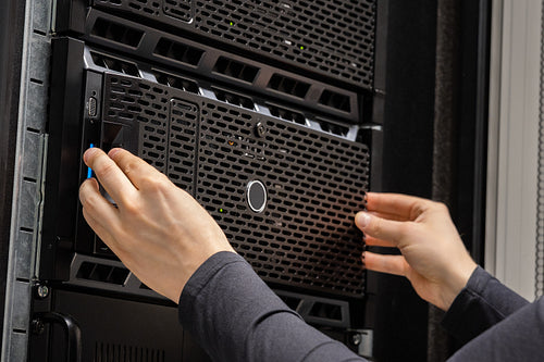 Close-up of hands Of IT Consultant Installing Servers In Datacenter