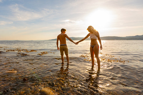Beautiful couple holding hands and walks at the sea shore in the evening