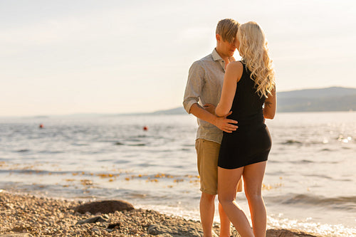 Beautiful young couple in romantic embrace on beach at summer