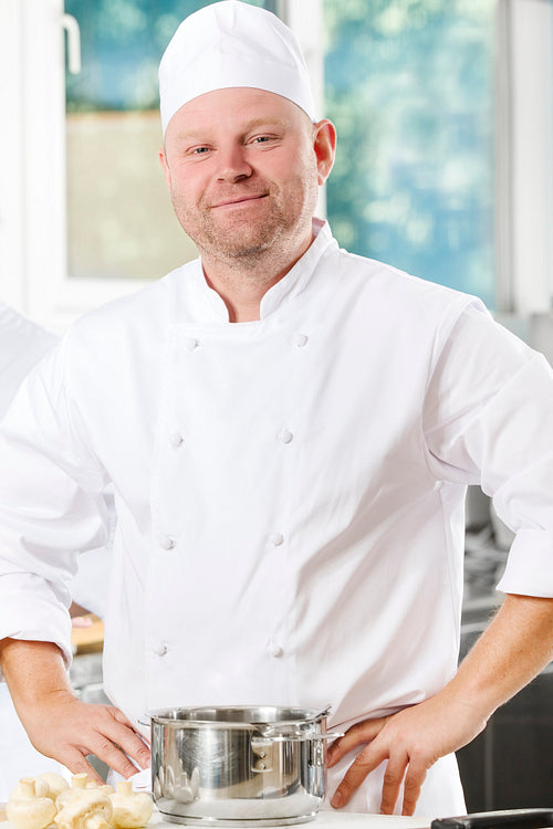 Confident and smiling chef standing in large kitchen