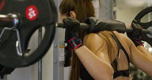 Close-up of a strong woman doing squats workout with heavy weights