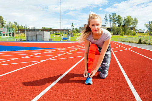Confident Woman Tying Shoe Lace On Running Tracks