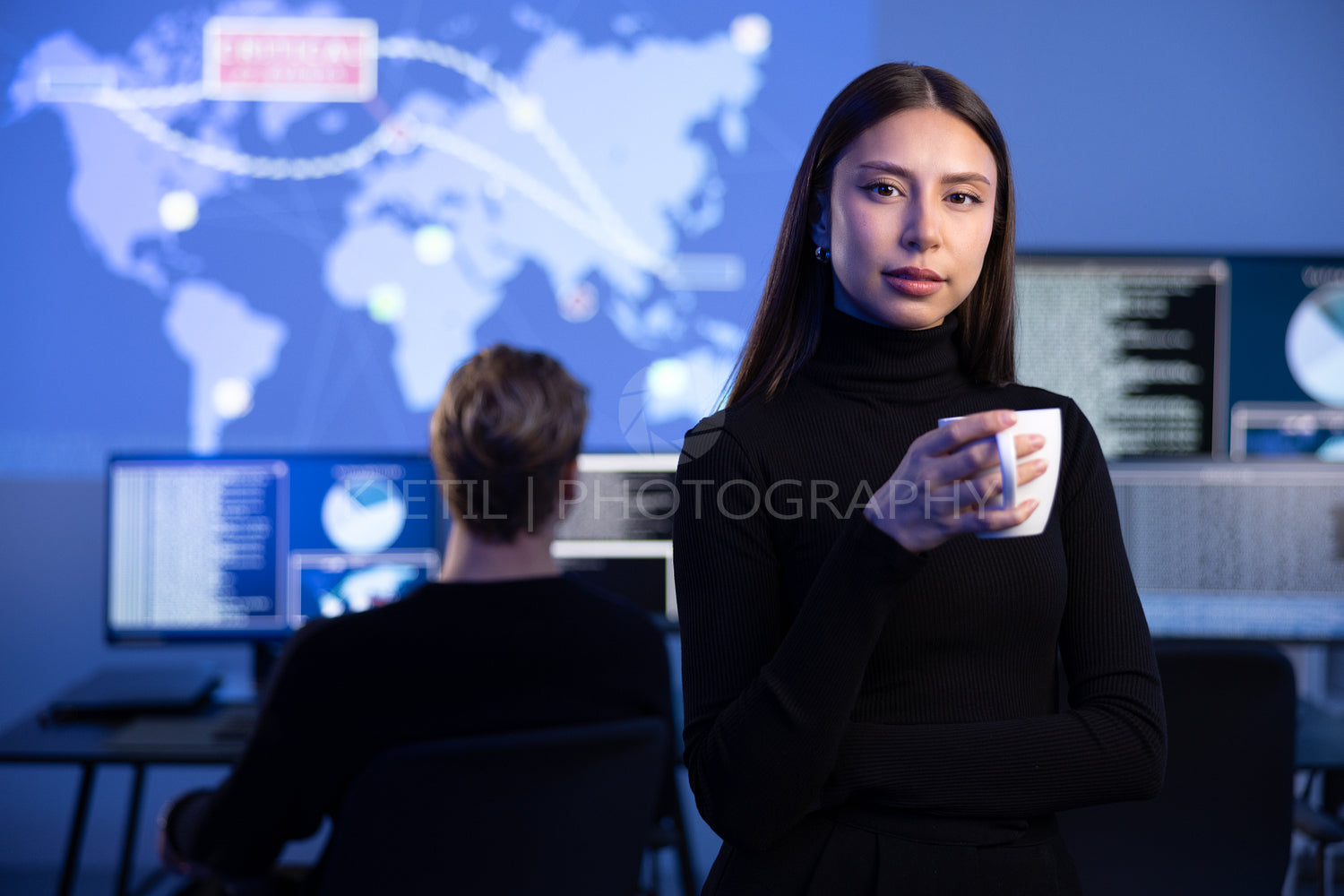 Professional Female IT Consultant holding coffee cup in large Cyber Security Operations Center SOC handling Threats