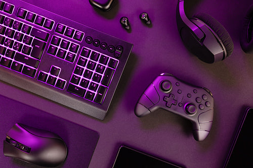 Purple lit keyboard amidst various devices