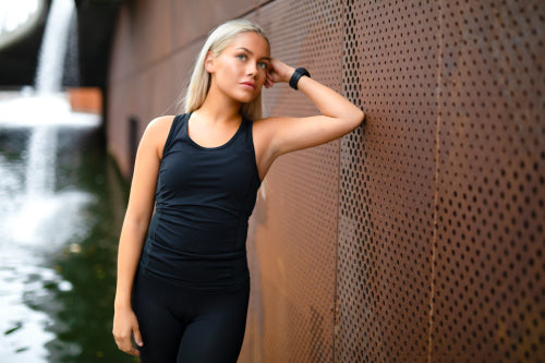Beautiful Woman in Sportswear Leaning On Metallic Wall After Workout