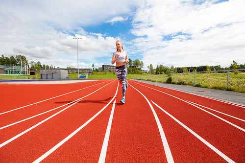 Fast athletic female runner on outdoor running track