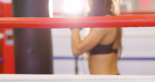Close-up of female boxer resting with her arms on the ring ropes