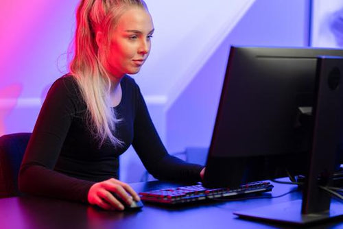 Focused Blonde Gamer Girl Playing Online Video Game on Her Personal Computer.