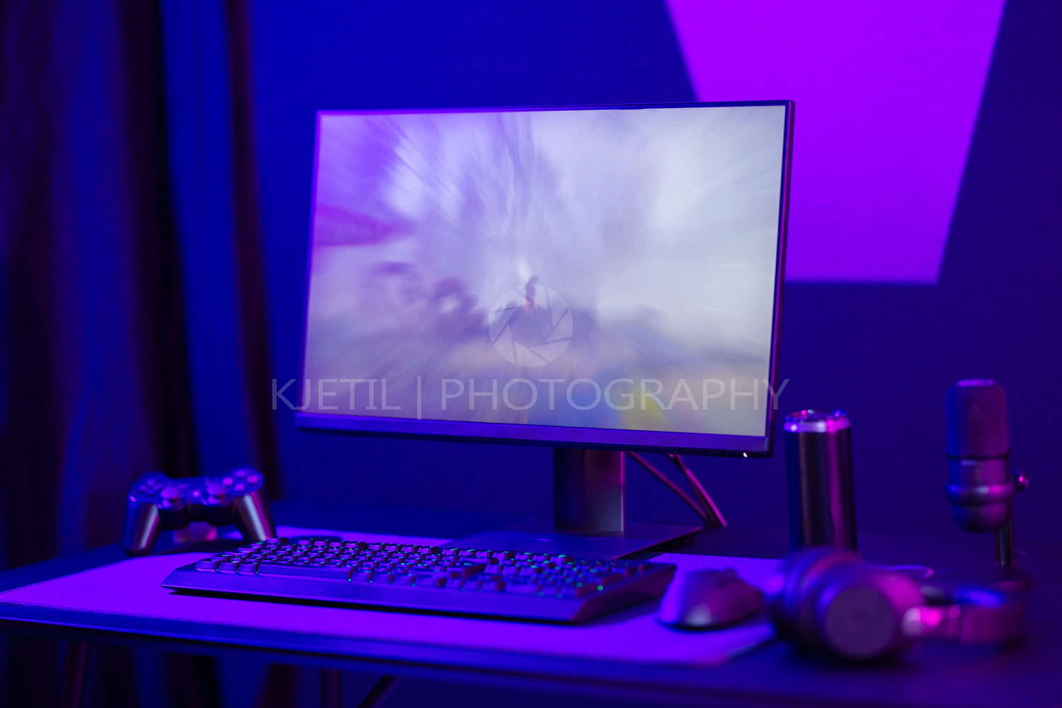 Modern gaming setup with controller, keyboard, and mic in purple lighting