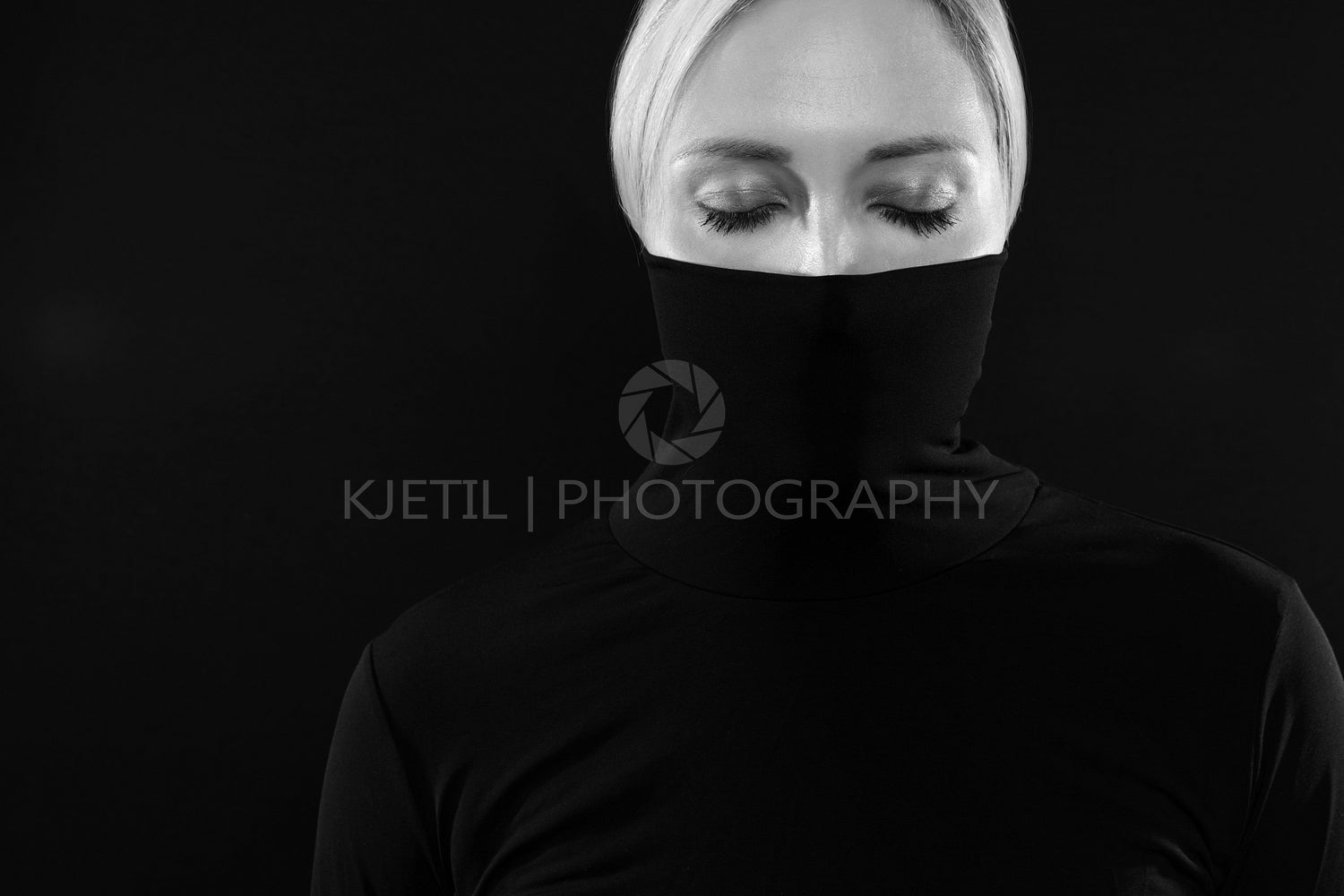 Black and white portrait of woman hiding face in black turtleneck