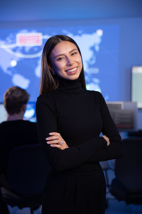 Smiling Confident Female Cybersecurity Analyst or Manager in large Cyber Security Operations Center SOC handling Threats