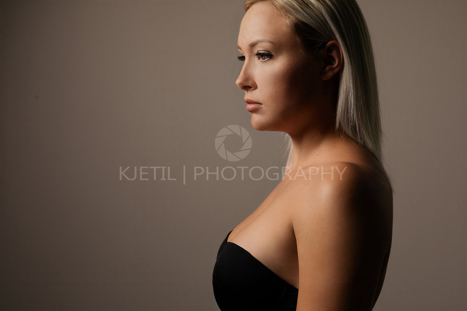 Dark studio portrait of gorgeous natural woman with blonde hair on brown background