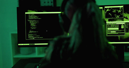 Cyber security hacker code malware to exploit vulnerability in program or system on a computer in a dark room