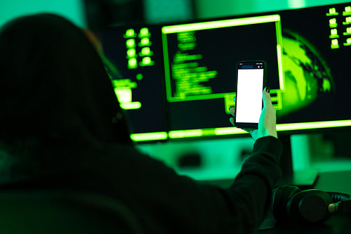 Hacker using smartphone in dimly lit cyber security environment