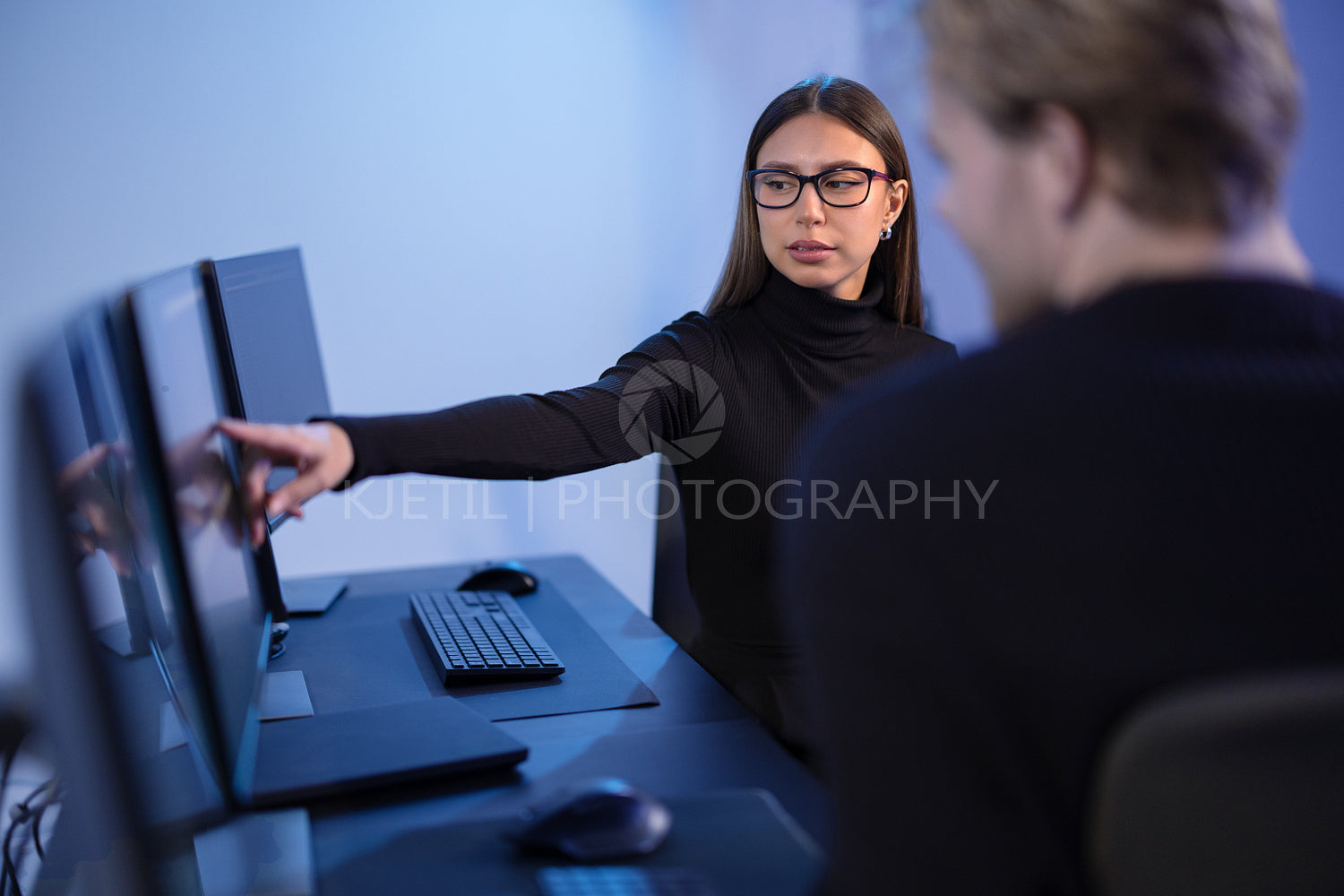 Cybersecurity professionals discussing and analyzing network security data on multiple screens in office