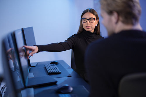 Cybersecurity professionals discussing and analyzing network security data on multiple screens in office