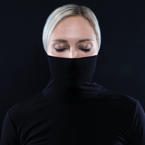 Studio portrait of beautiful elegant woman hiding face in black turtleneck