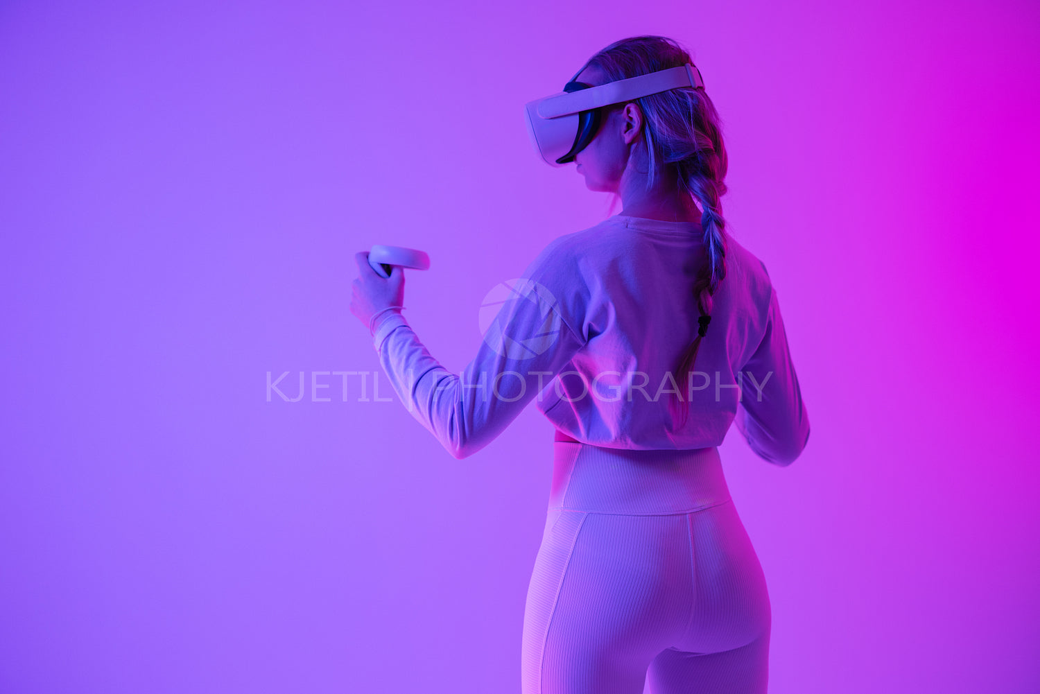 Woman experiencing virtual reality in vibrant neon purple lighting