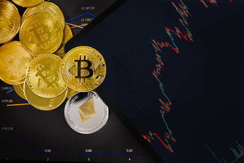 Golden bitcoin and crypto coins by digital tablet over chart