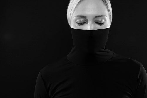 Black and white portrait of woman hiding face in black turtleneck
