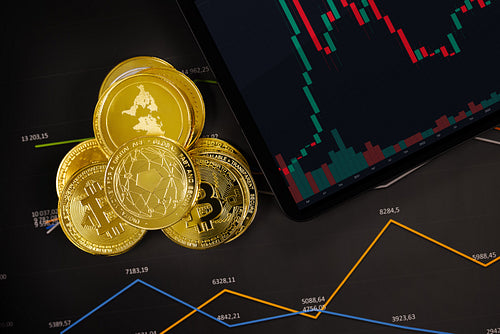 Bitcoin and crypto coins near digital tablet on graph