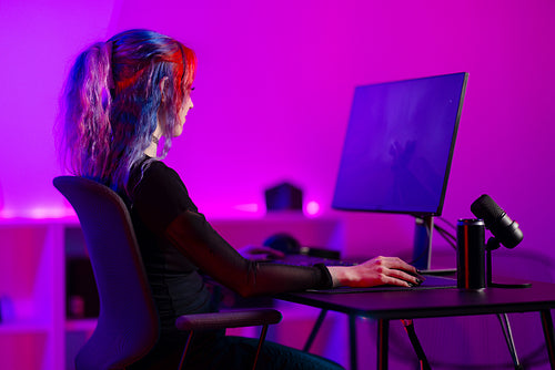 Professional gamer playing video game in colorful room with neon lights