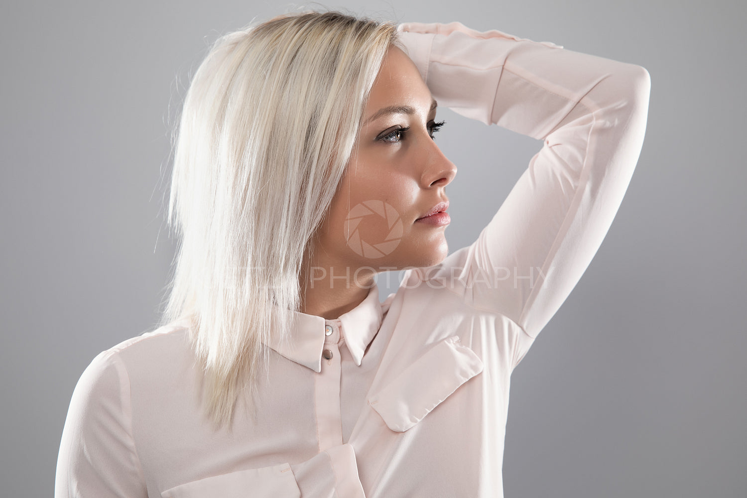 Beautiful female model in shirt holding her blonde hair