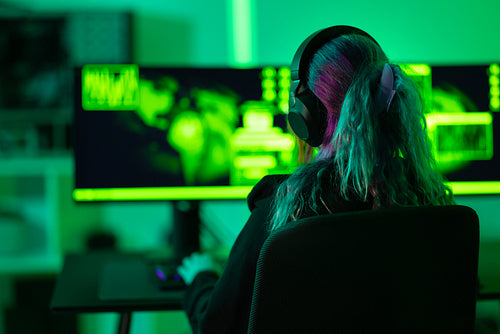 Female hacker working on cybersecurity tasks in a green lit room