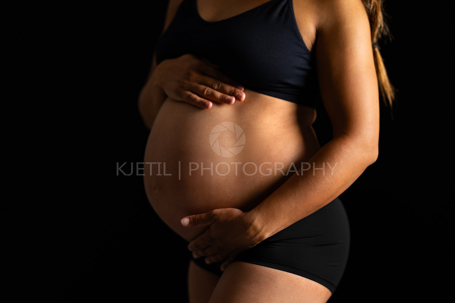 Pregnant Woman Embracing Her Belly in Dark Backdrop
