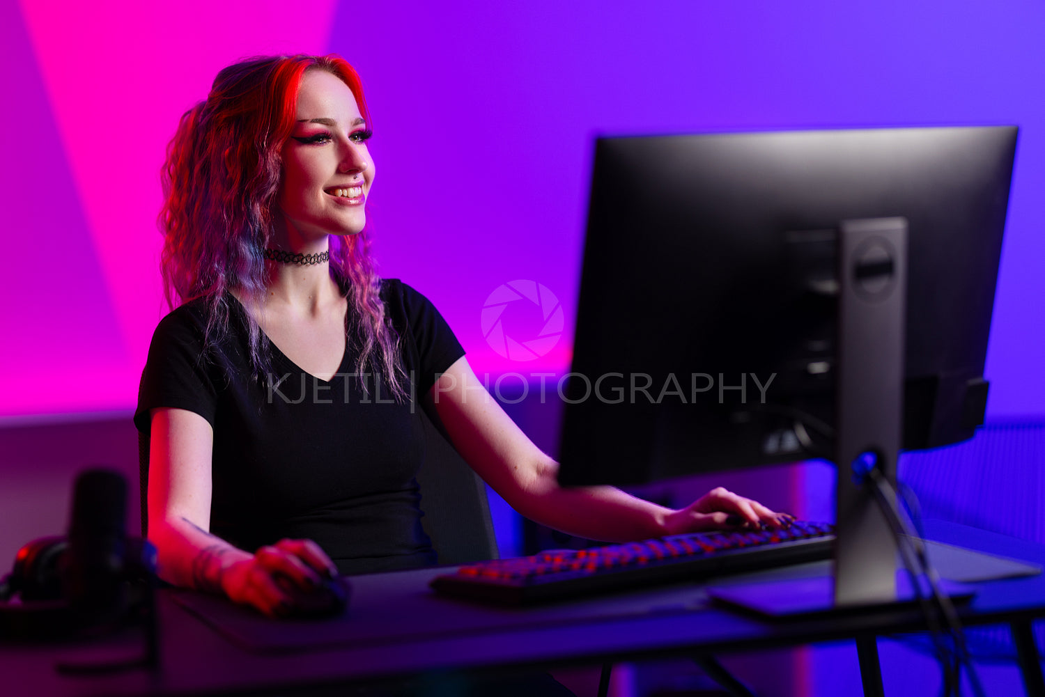 Professional gamer smiling while playing a PC game in a vibrant room with neon lighting