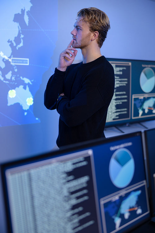 Thoughtful Cyber Security Control Center Operator Working. Multiple Screens Showing Technical Data and Alerts.