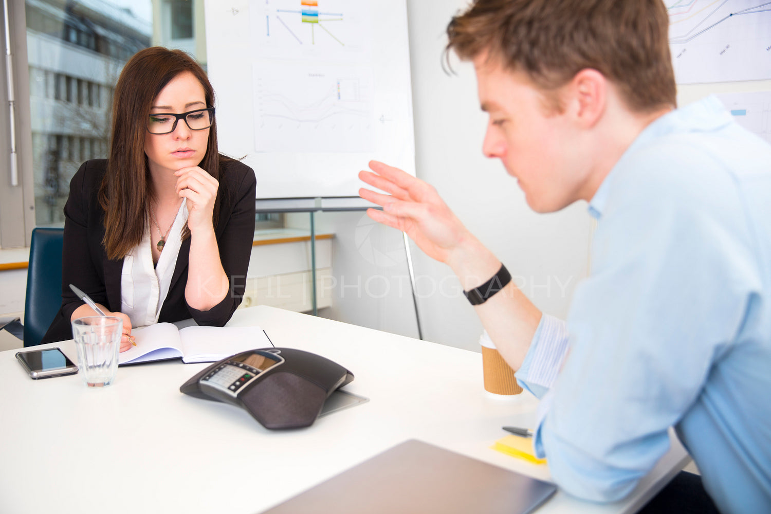 Business People Using Conference Phone At Meeting Desk