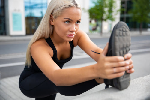 Determined Woman Doing Stretching Exercise At Sidewalk Railing